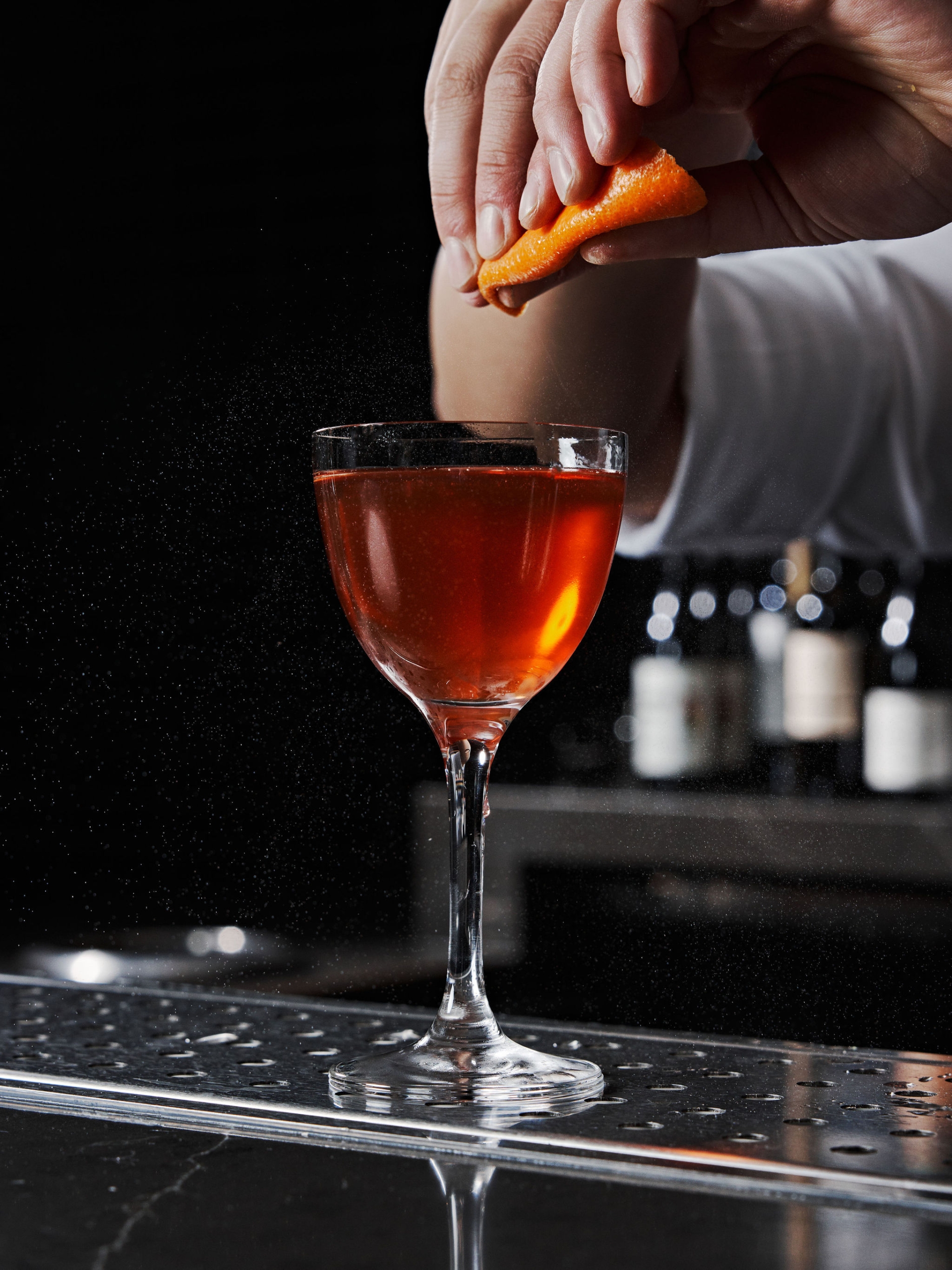 The bartender squeezes an orange rind over a cocktail at No. 119 at Asher Adams Hotel, Salt Lake City