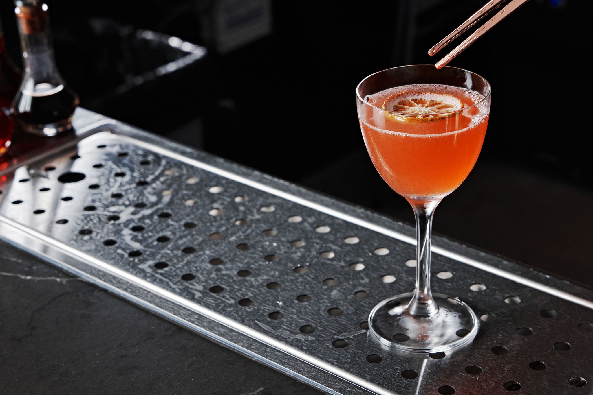 A bartender uses tweezers to place the finishing touches on a pink cocktail at No. 119 at Asher Adams Hotel, Salt Lake City