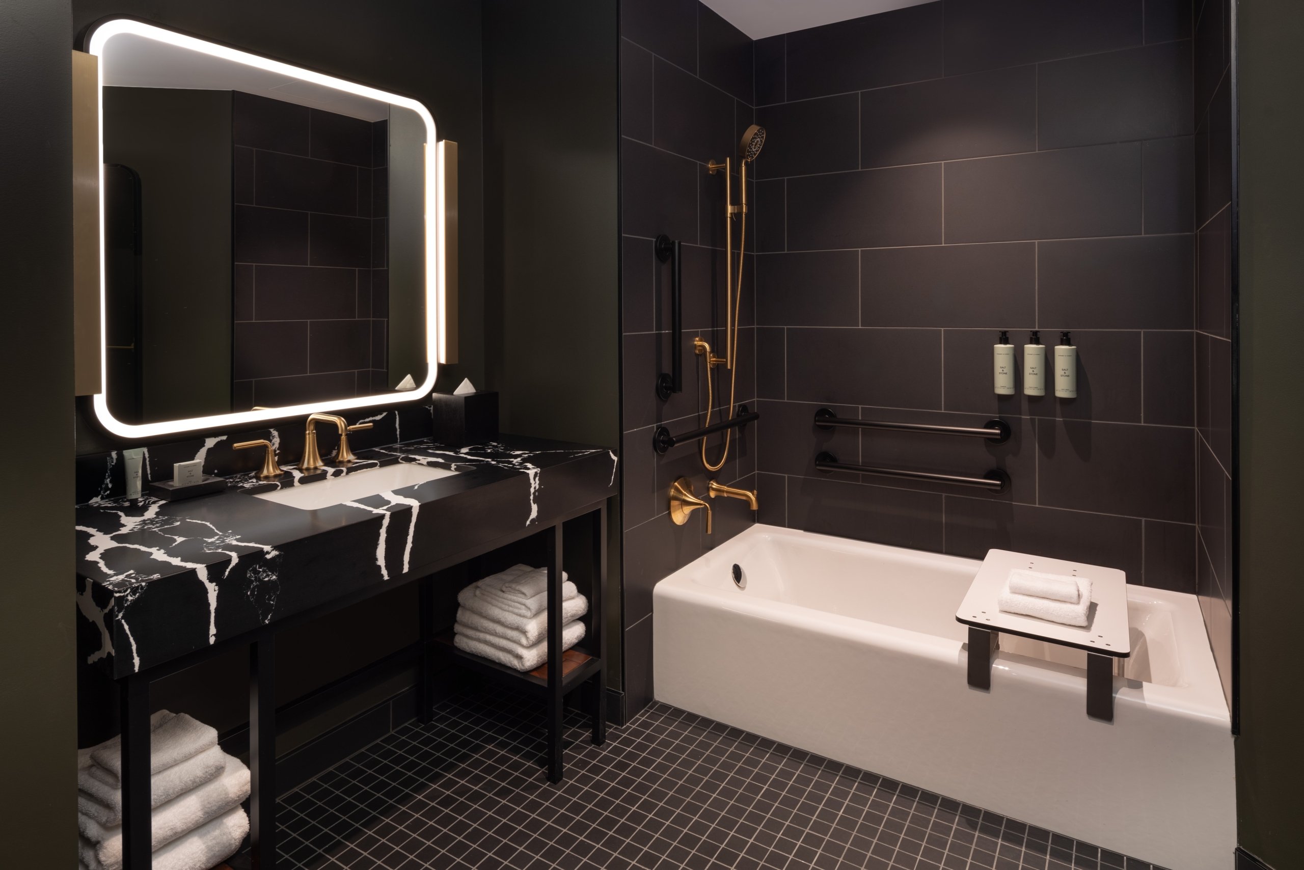 An ADA accessible tub with hand rails and roll up sink in a guest room at Asher Adams Hotel, Salt Lake City