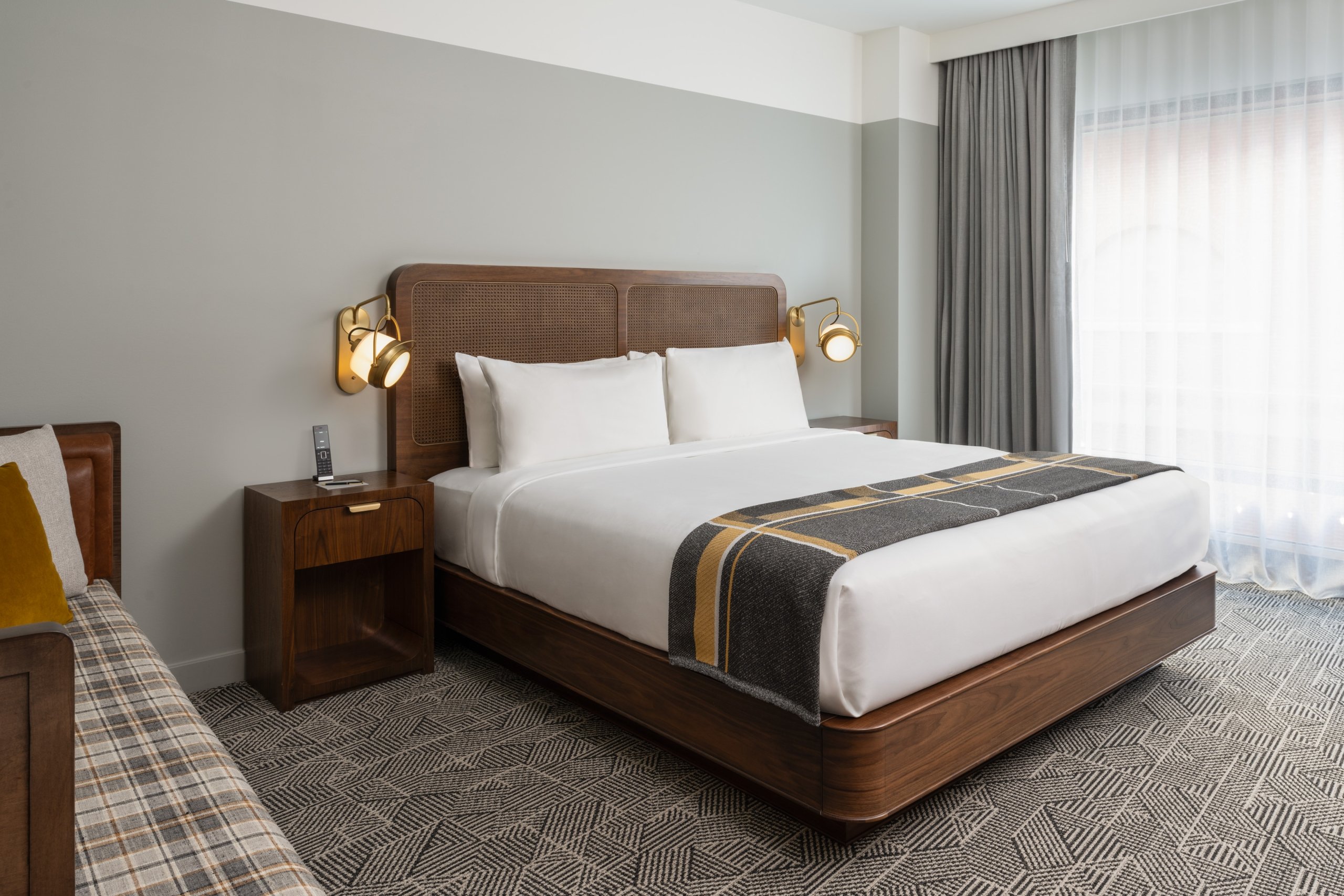 A chaise and king bed in a suite at Asher Adams Hotel in Salt Lake City