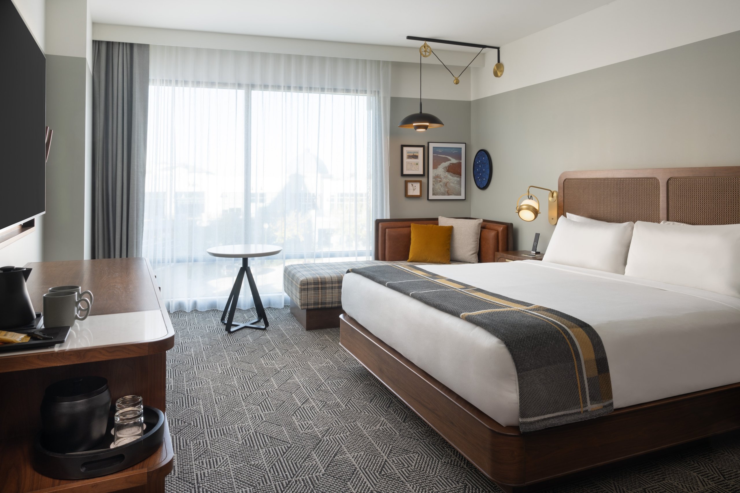 A chaise and a king bed in a suite with a balcony at Asher Adams Hotel in Salt Lake City