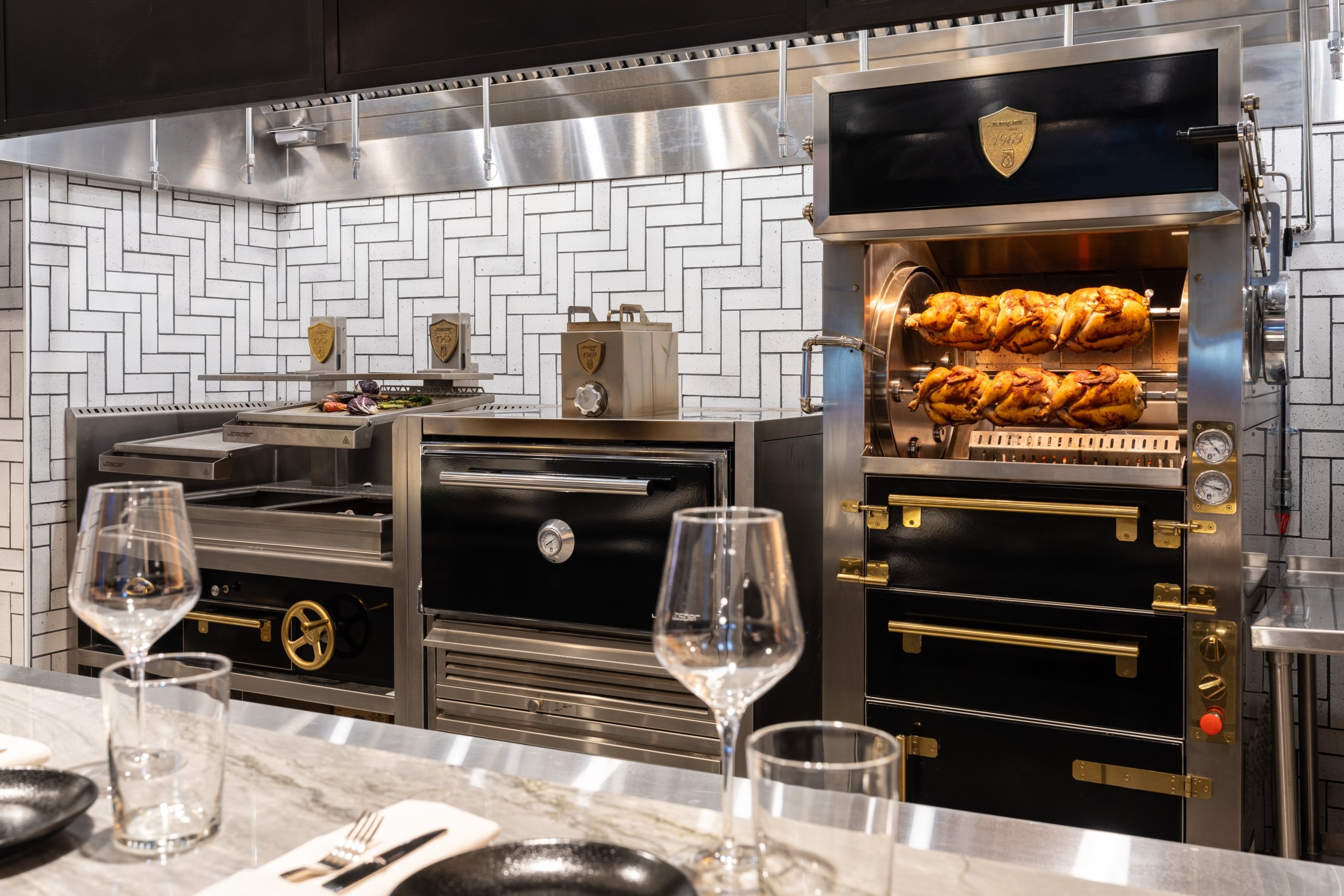 A professional kitchen with chickens on a spit roaster