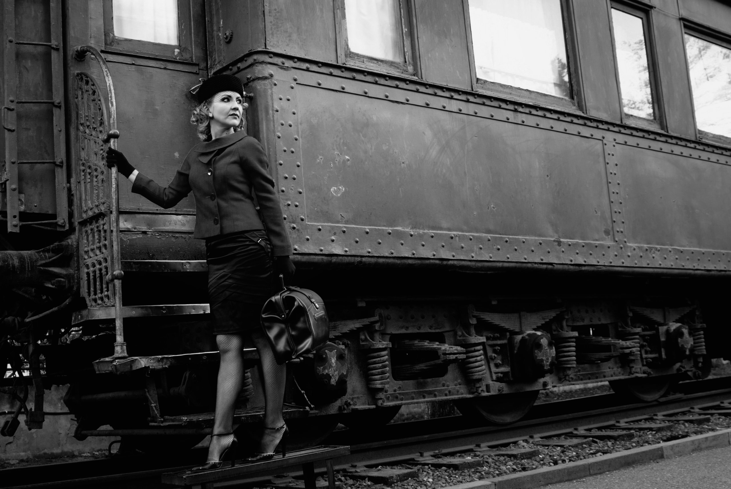 A woman in professional, old-time dress boards a steam engine train