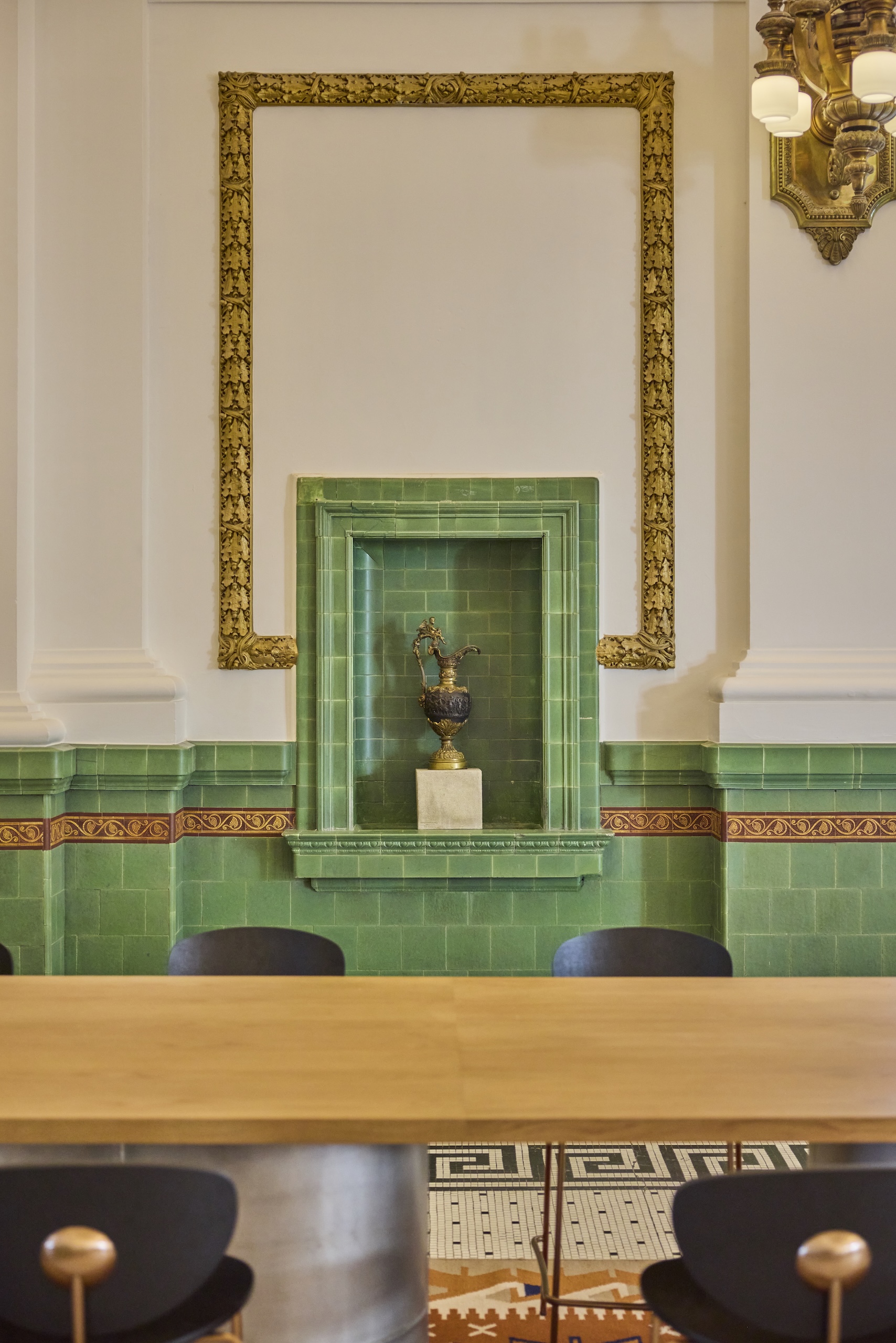 An ornate green tiled wall with a historic golden pitcher on display at Asher Adams Hotel, Salt Lake City.