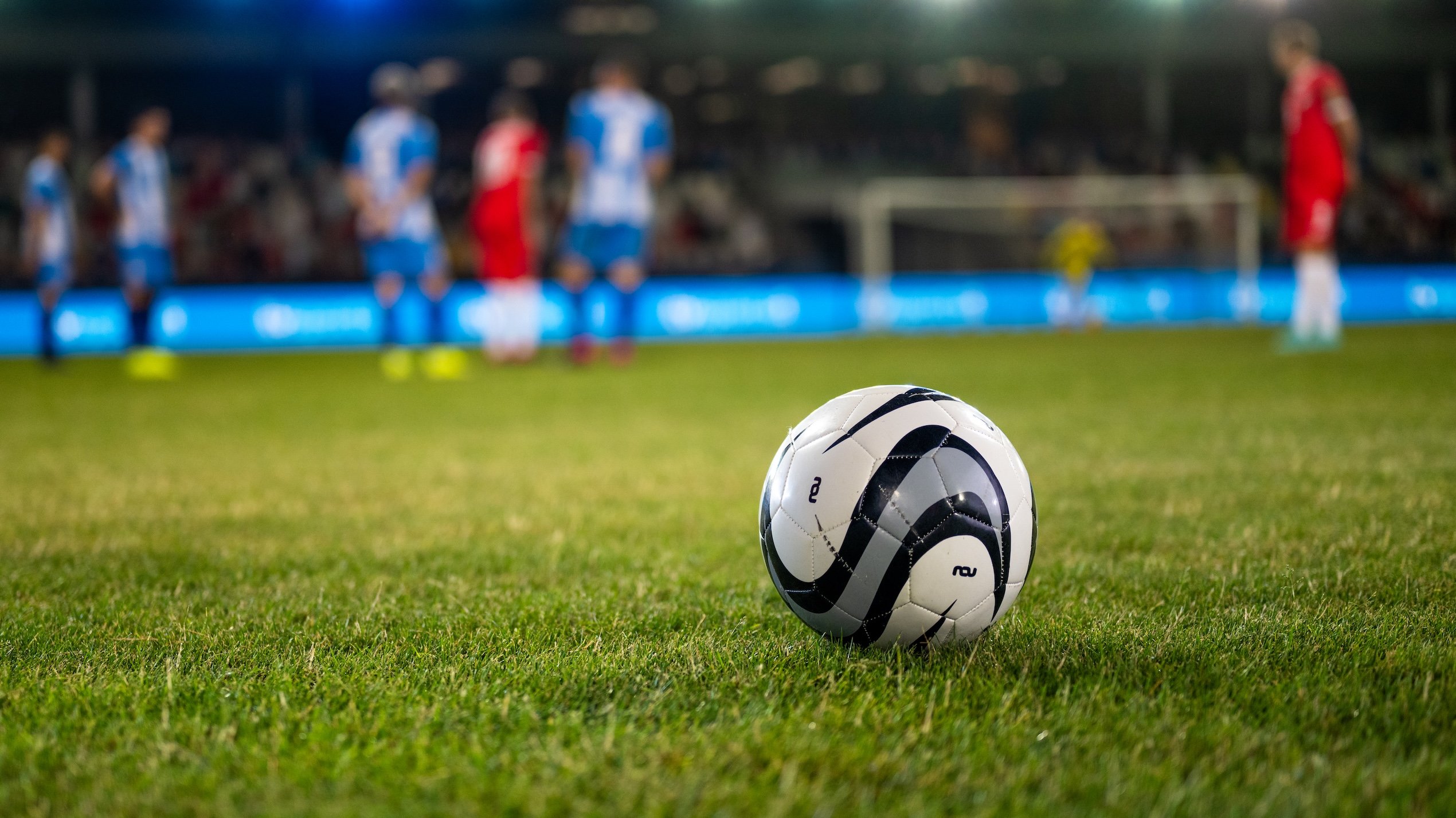 Football kept on grassy football pitch.