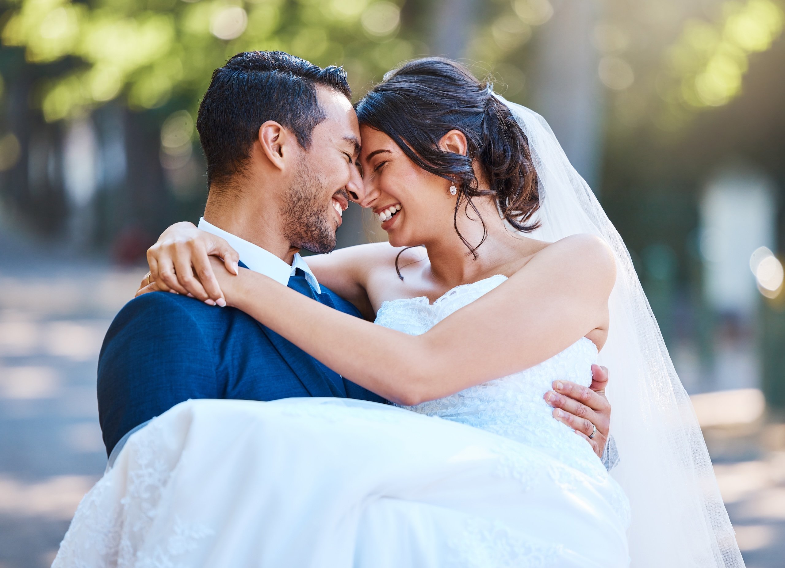 Loving groom carrying his bride in his arms in nature.