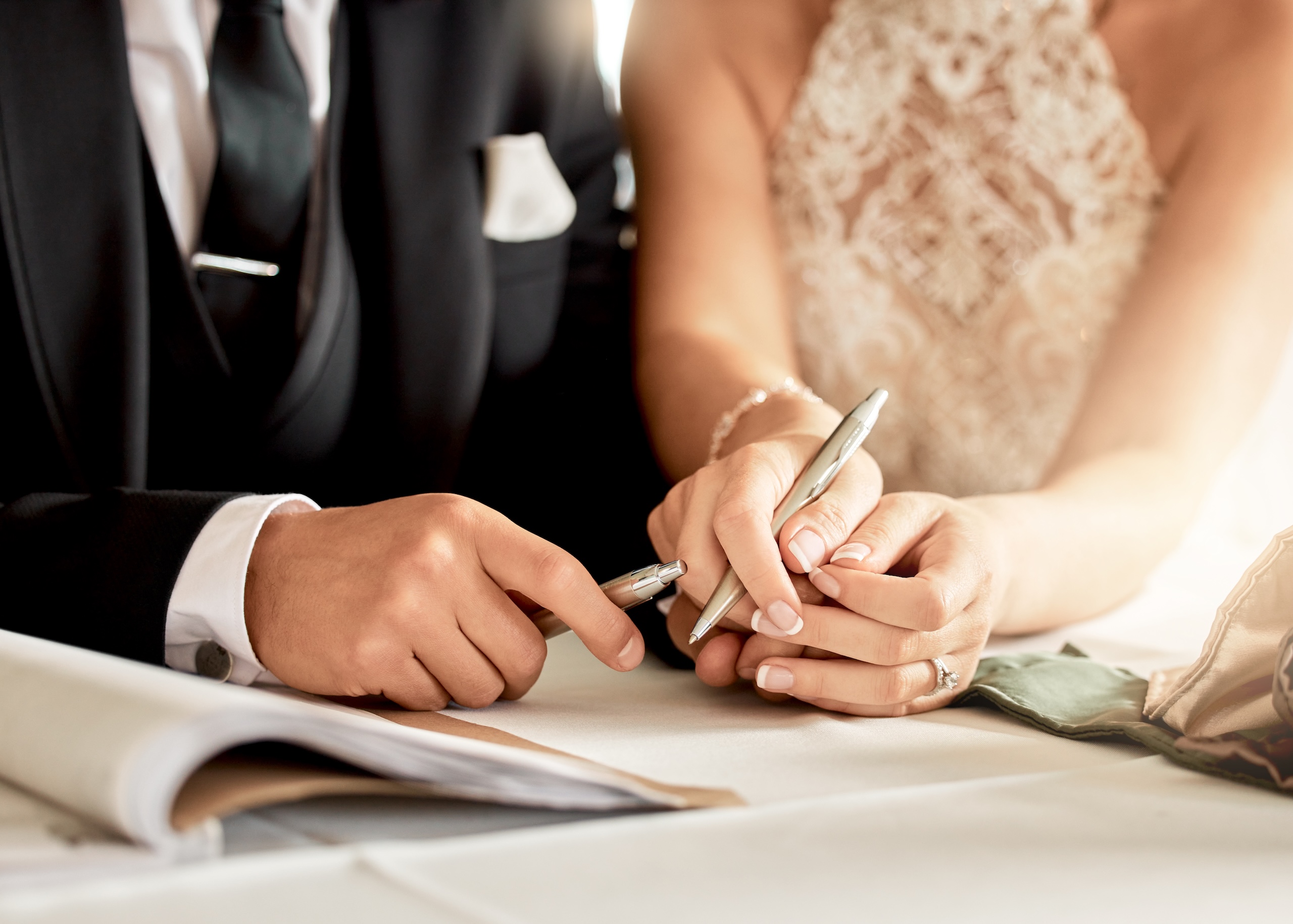 Couple sign wedding certificate, marriage registration and document paper for legal union.