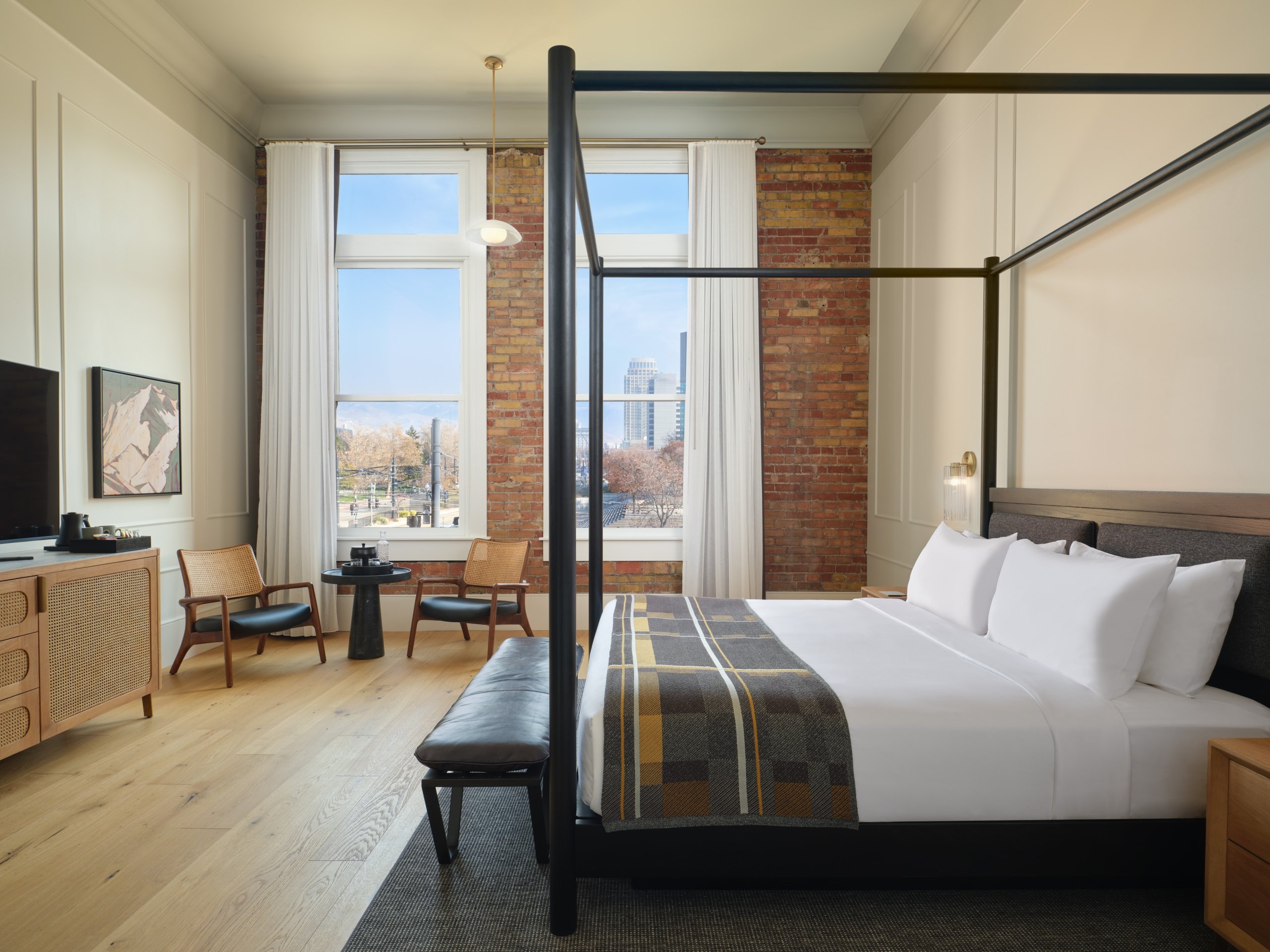 A four-poster bed and sitting area in a suite at Asher Adams Hotel with views of downtown Salt Lake City