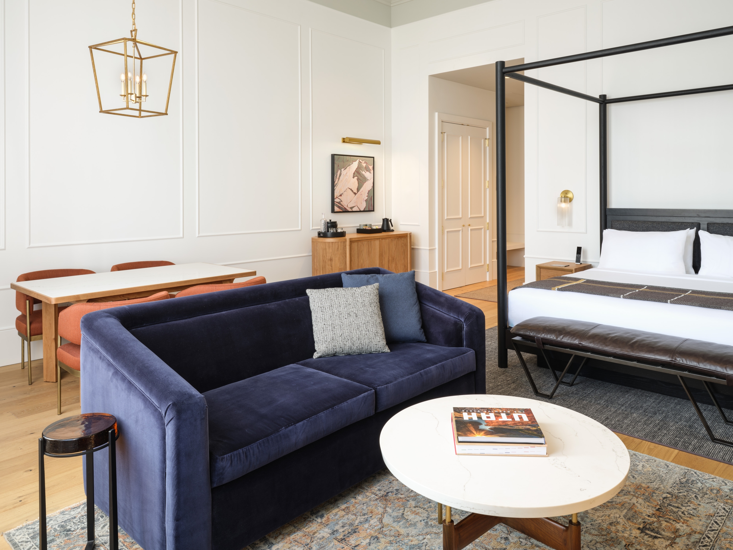 A four-poster bed, living and dining areas in a suite at Asher Adams Hotel, Salt Lake City