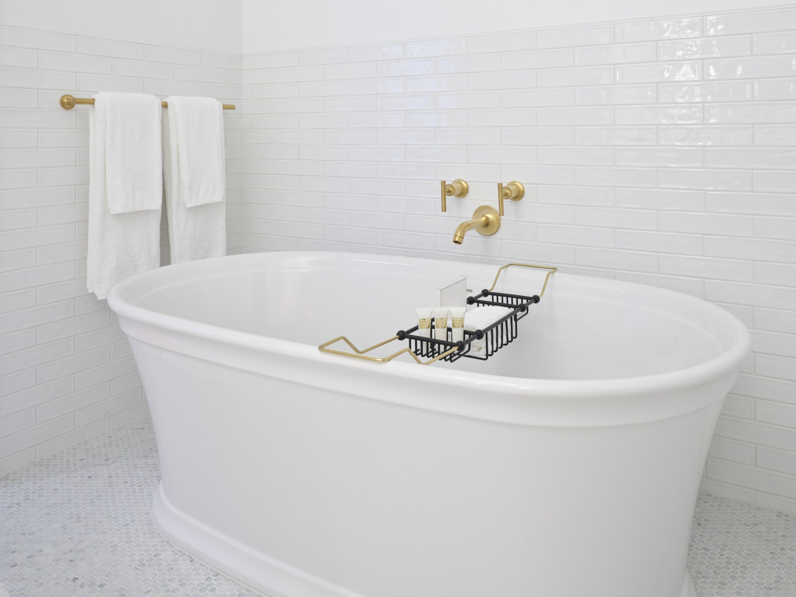 A large soaking tub in a white tiled bathroom in a suite at Asher Adams Hotel, Salt Lake City