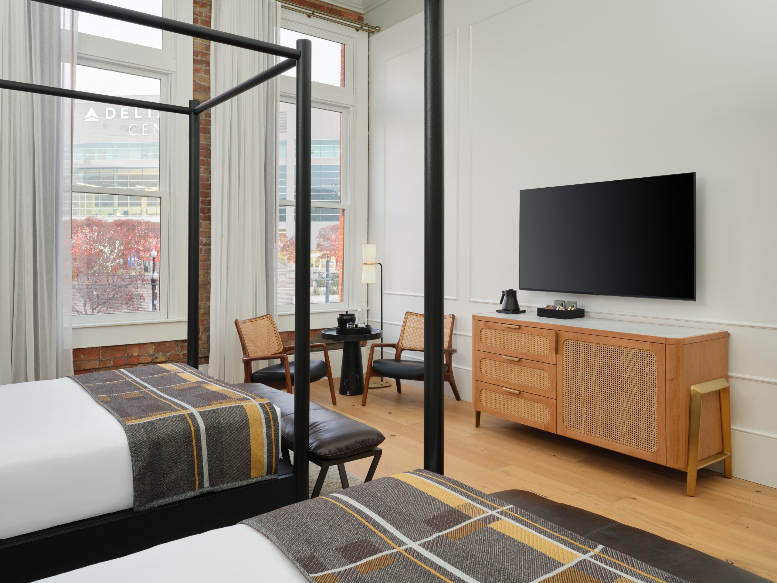 Two four-poster queen beds and a tv in a suite at Asher Adams Hotel, Salt Lake City