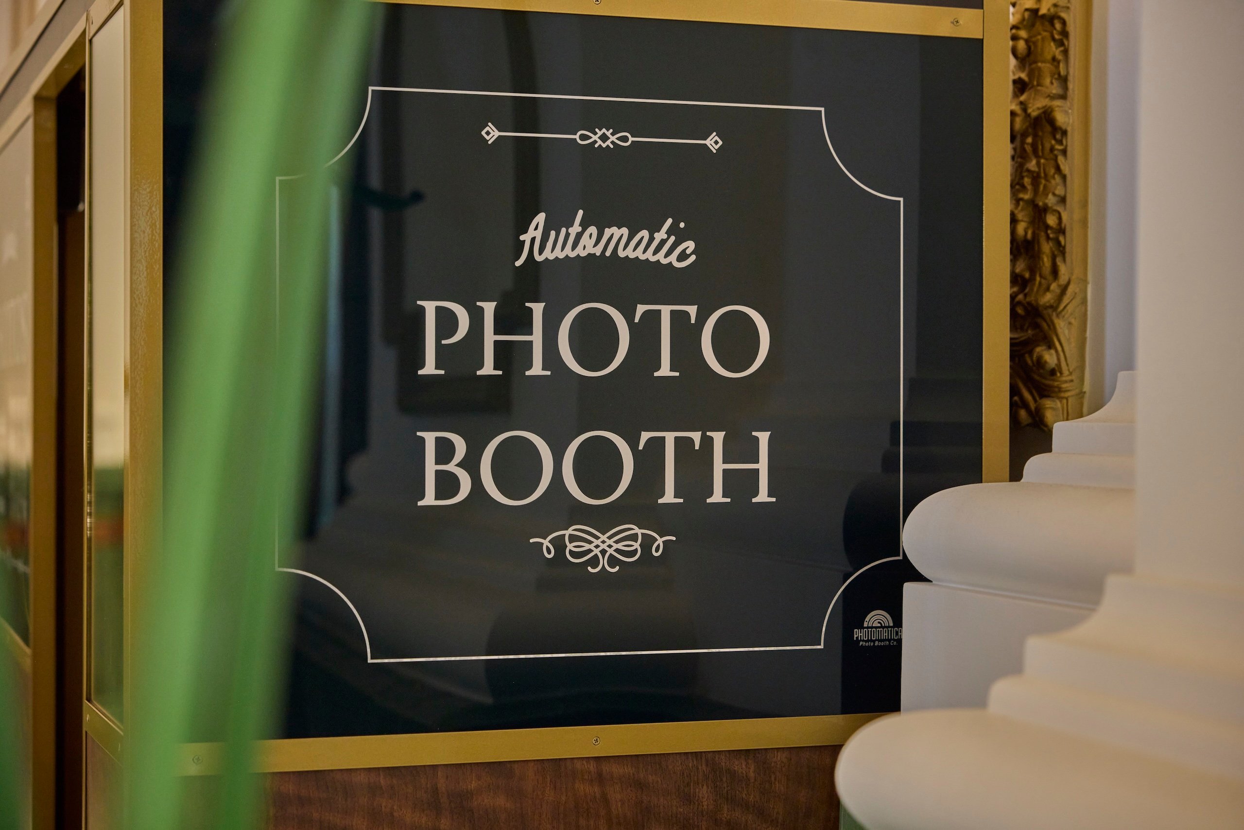 A close up of the Automatic Photo Booth sign at Asher Adams, in decorative font.