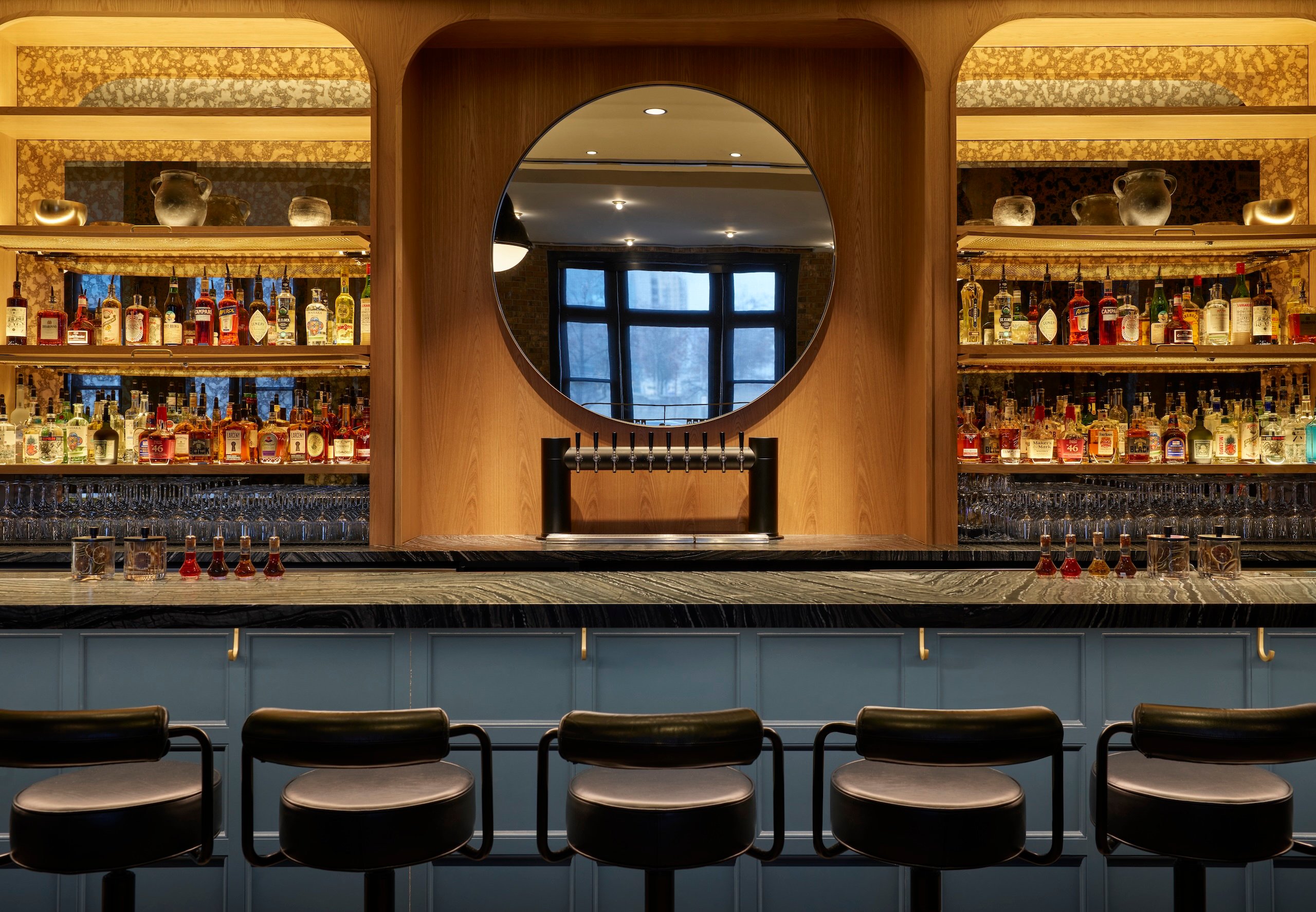 Bar stools and shelves of alcohol bottles inside Rouser at Asher Adams Hotel, Salt Lake City